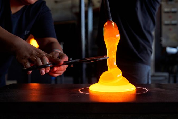 Unrecognizable men cutting liquid glass in workshop