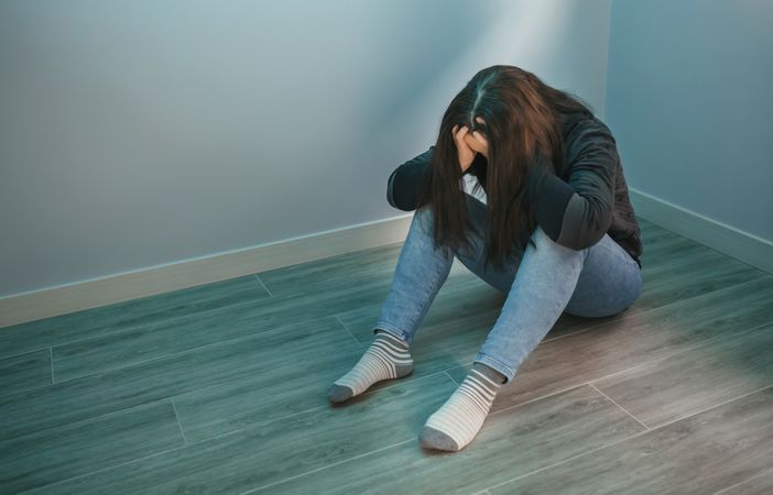 Sad woman with hands in head sitting on the floor