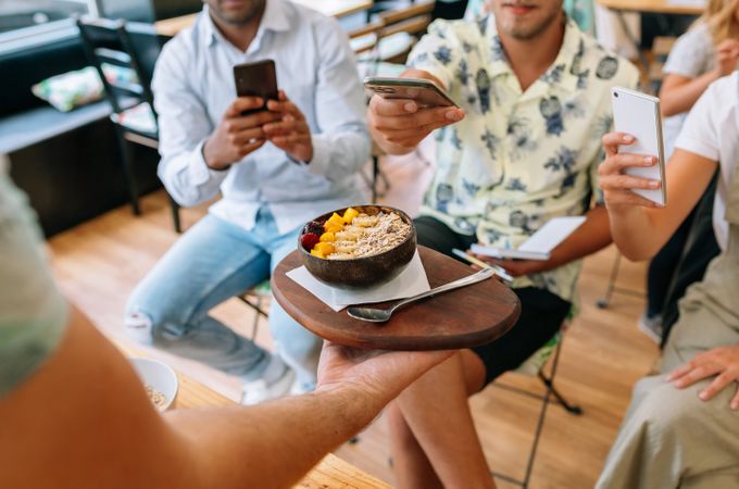 Unrecognizable chef showing exotic dish to food bloggers taking pictures during cooking master class