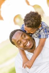 Black Father and Son Playing Piggyback in sunny Park