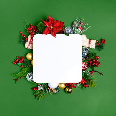 Christmas decoration flat lay with a blank mockup card on a green background.