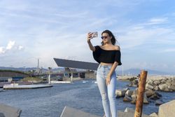 Female traveler in sunglasses taking selfie in Barcelona city on the coast