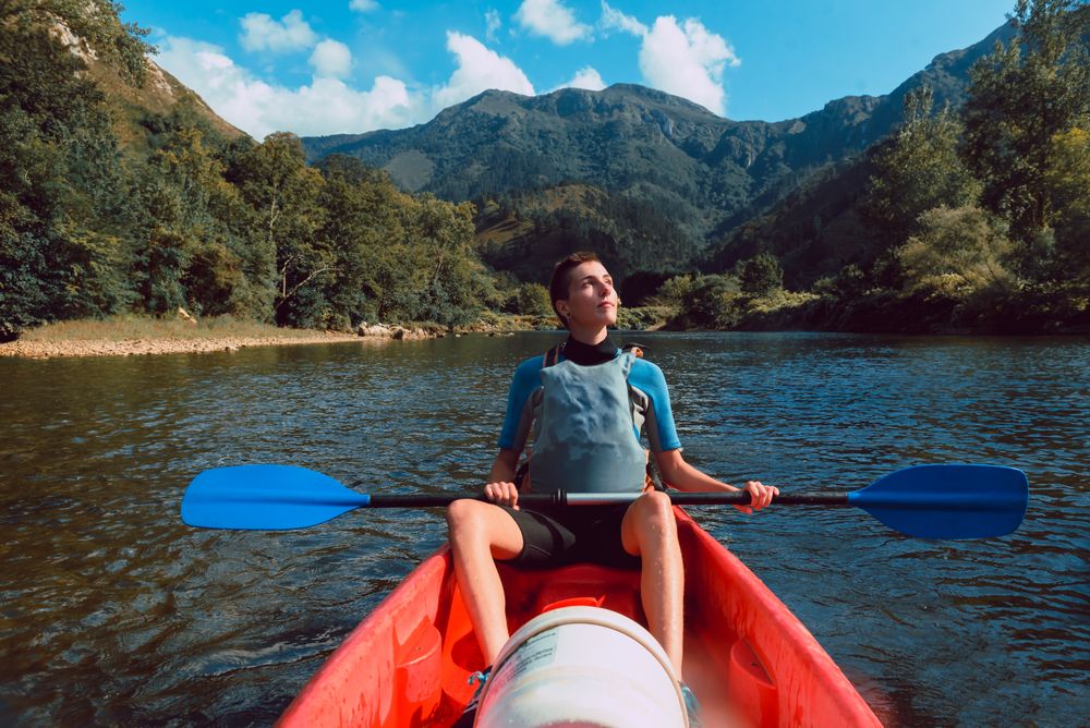 Young female kayaking on nature background