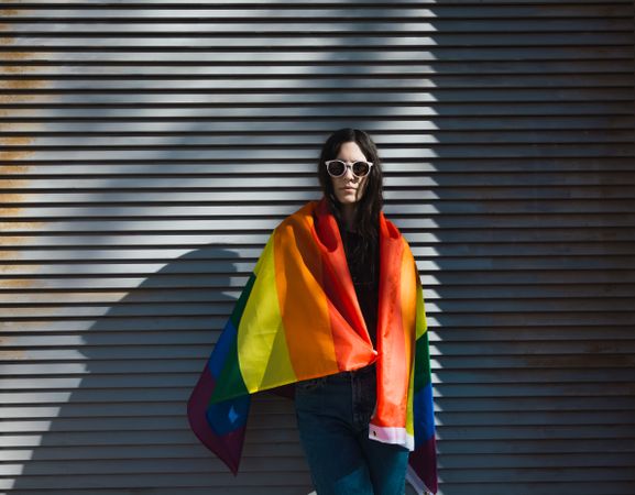 Woman posing happily with a rainbow flag