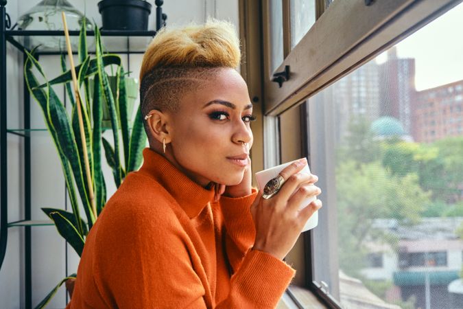 Black woman thinking deeply over a cup of coffee while looking out a window