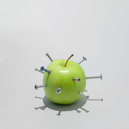Green apple stabbed with many screws