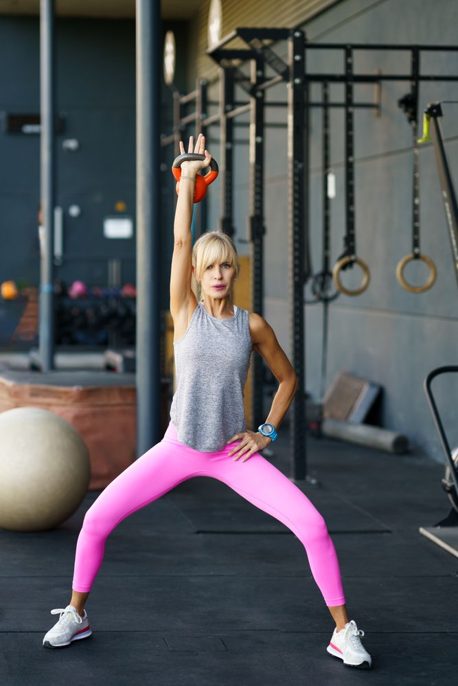 Fit woman using kettle bell in gym