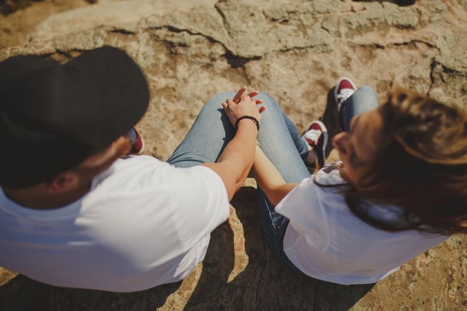 Happy couple sitting at mountain cliff