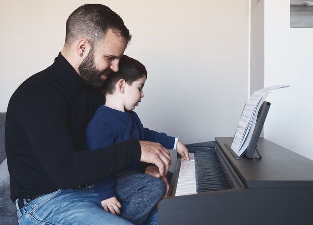 Father teaching son to play piano