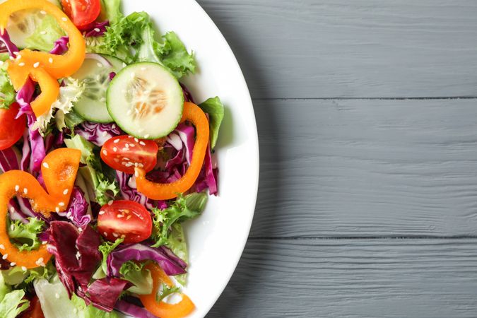 Plate with fresh salad on wooden background, space for text