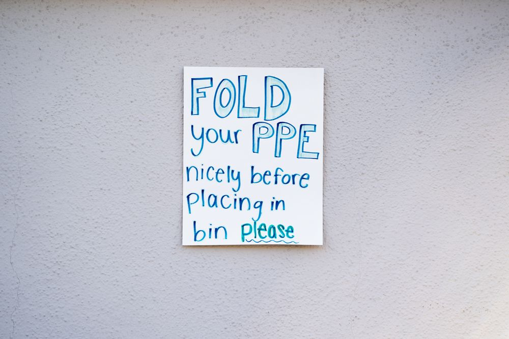 Sign at public pandemic testing site requesting medical workers to fold their PPE