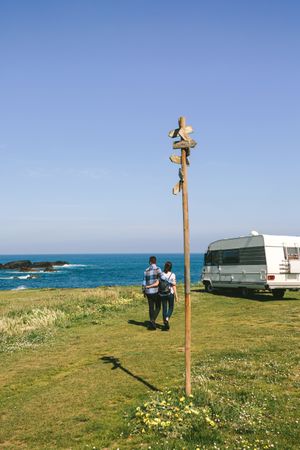 Couple taking a walk near the coast with a camper