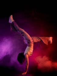 Young woman break dancing in colorful smoke