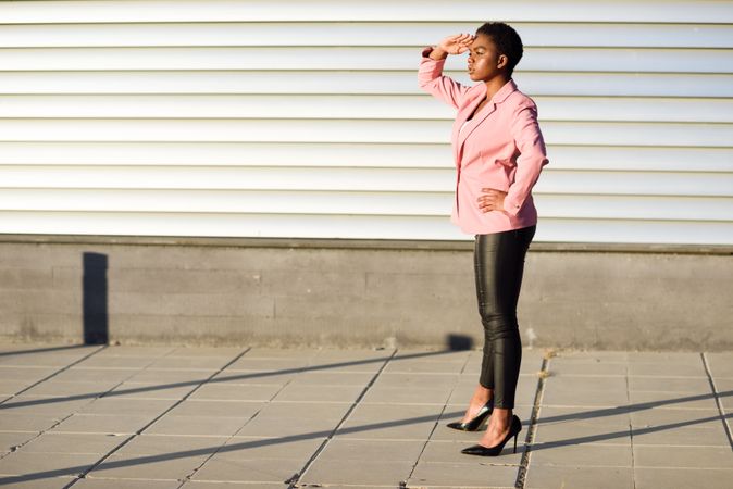 Female in modern business suit with hand protecting her eyes from the sun
