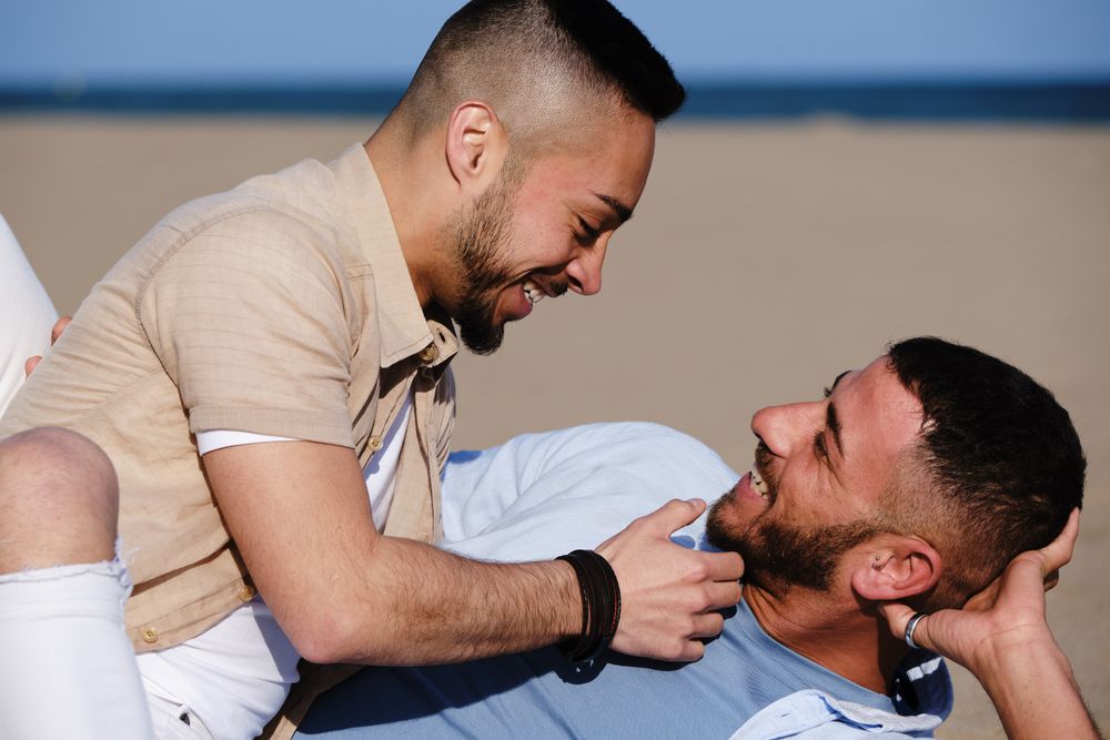 Affectionate gay couple relaxing on beach