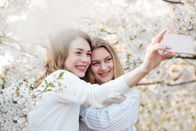 Friends taking selfie near blooming trees