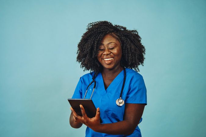 Portrait of smiling Black medical professional dressed in scrubs with tablet