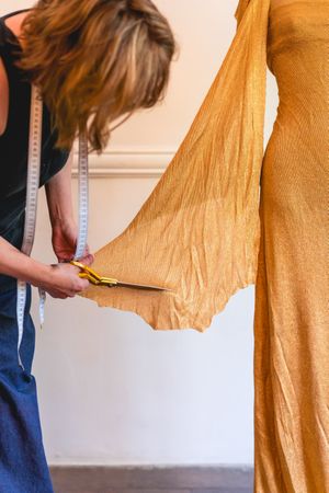 Fashion designer using textile scissors to work on clothing design. Vertical shot
