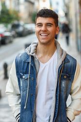 Smiling man in jean jacket walking on street