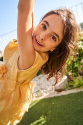 Satisfied Hispanic child riding rope swing in backyard