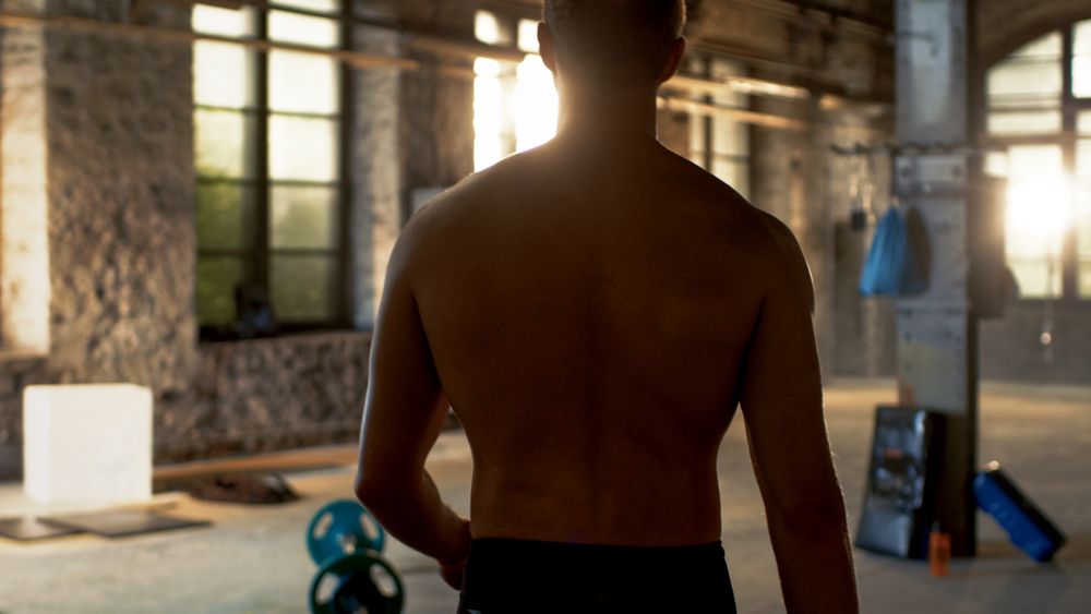 Shot from the back of Muscular Shirtless Man Entering Gym.