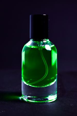 Green perfume bottle in dark studio