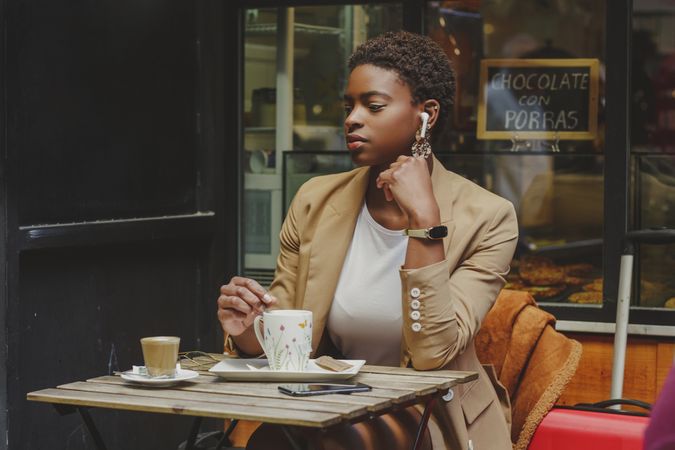 Black woman with cup of drink sitting at table in cafe