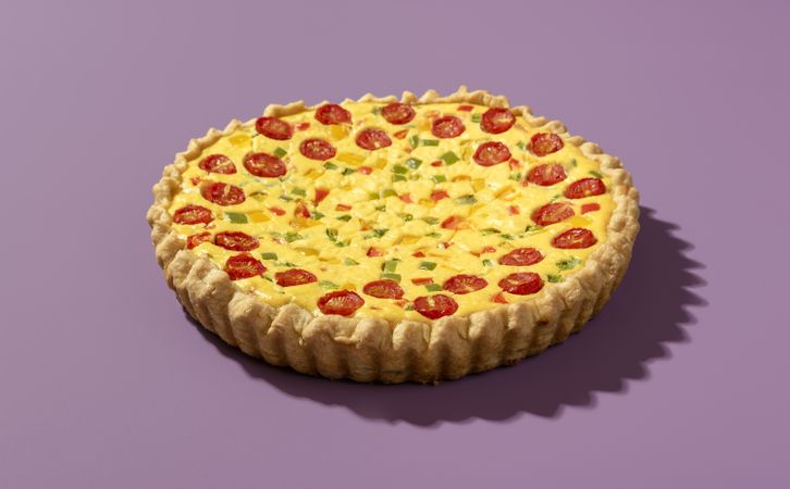Homemade quiche isolated on a purple background