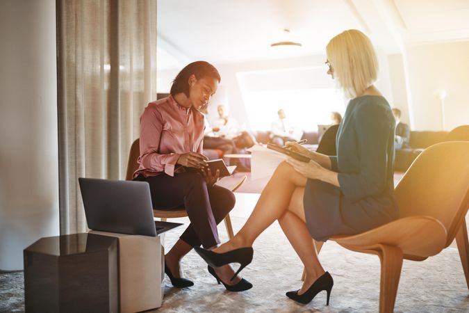 Two women sitting taking notes together