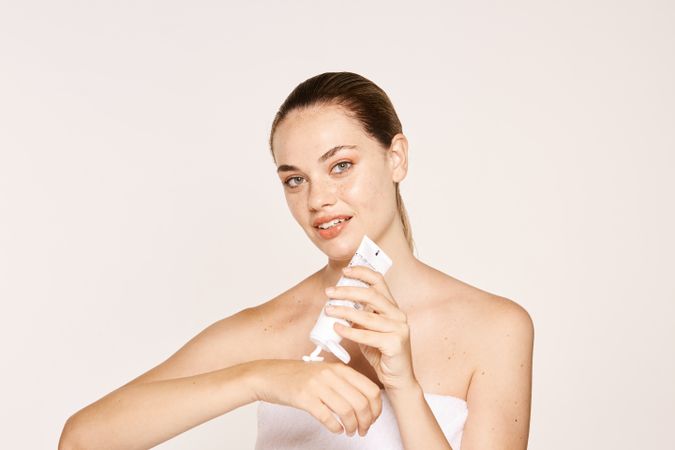 Appealing female applying moisturizing cream on hands