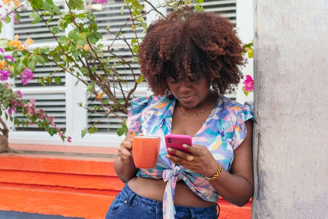 woman enjoying a coffee and looking at her cell phone on the street.