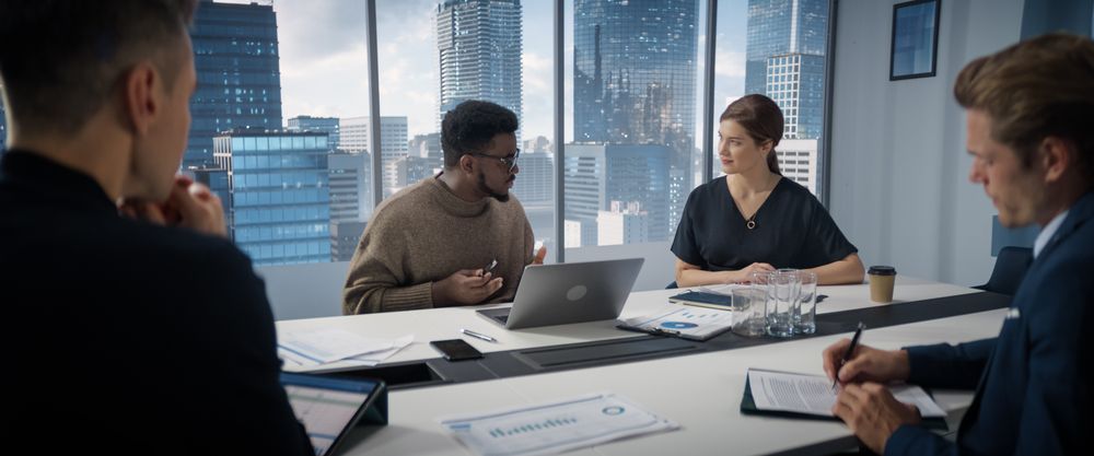 Multi-Ethnic Office Conference Room Meeting: Diverse Team of Top Managers Talk, Brainstorm Ideas, Use Laptop Computer.