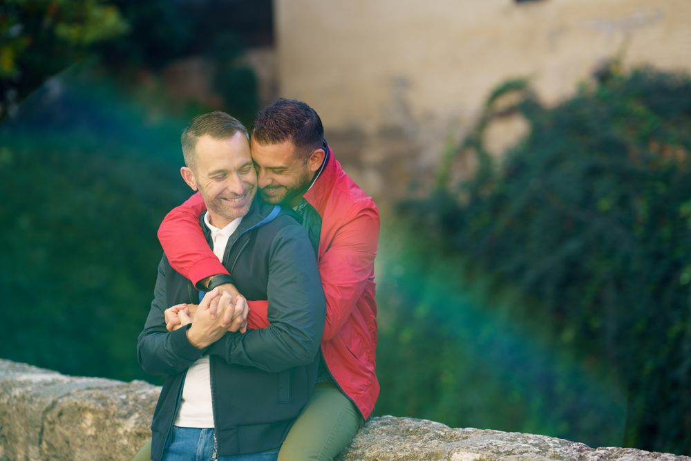 Cute male couple holding each other by the river, copy space