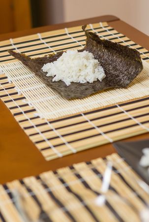 Nori seaweed sheet with rice above ready to make Japanese sushi rolls, vertical
