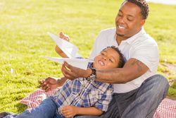 Smiling Father and Son Playing with Paper Airplanes