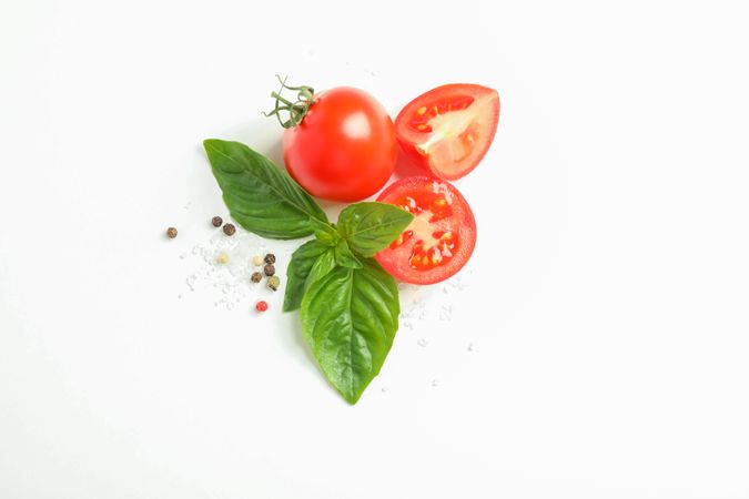 Fresh cherry tomatoes with basil and spices on blank background, space for text and top view. Ripe vegetables