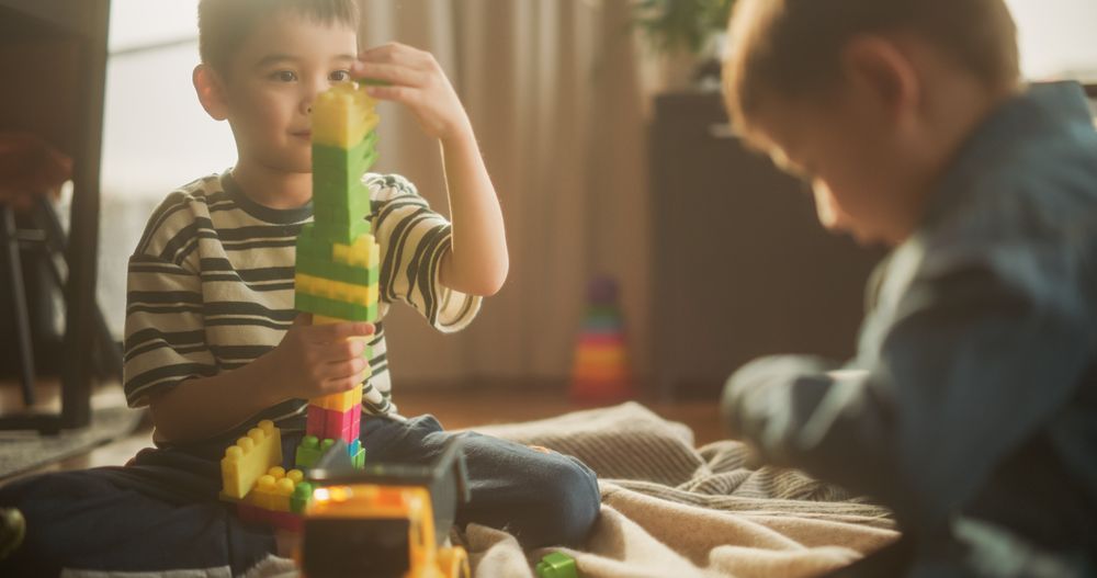 Portrait of Two Male Asian Kids Playing with Colorful Building Blocks in Their Room During the Day.