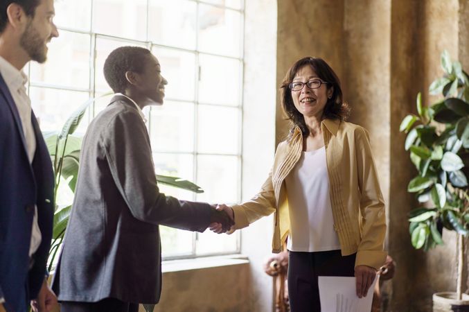 Black woman shaking hands with mature Japanese woman in office setting