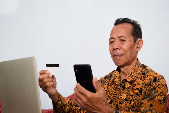 Older man holds and look at blank credit card