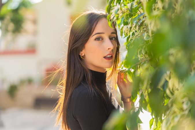 Charming woman beside bush leaves on street