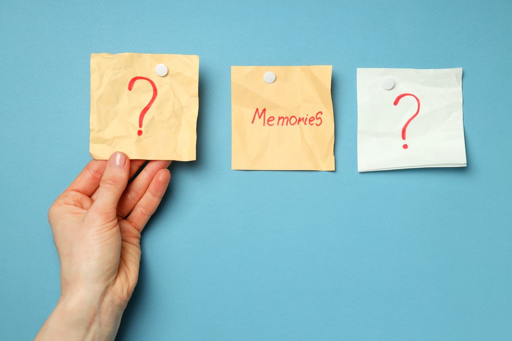 Person reaching for post it notes with question mark on blue board