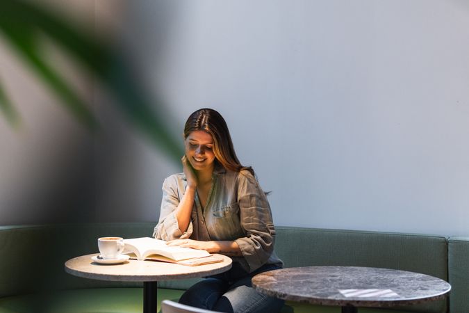 Smiling woman reading book at cafe table