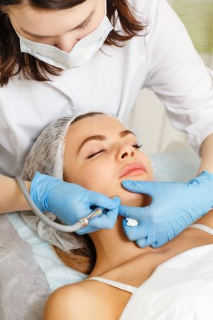 Woman having facial beauty treatment with machine on her jaw, vertical
