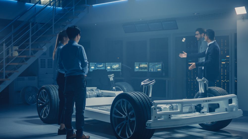 Automobile Engineers Discussing and Designing Electric Car Chassis Platform, Using Tablet Computers with 3D CAD Software.