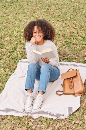 Cheerful Black woman with book in nature