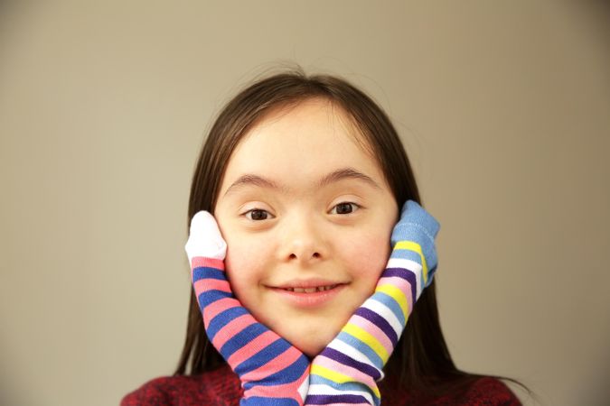 Close up of young child placing hands on face with socks covering hands