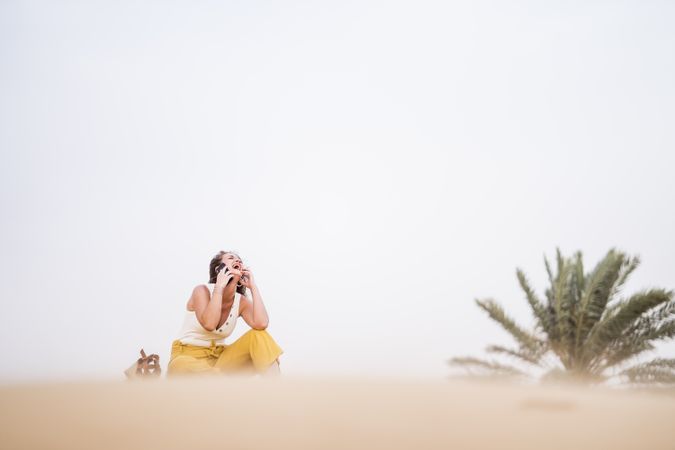 Happy woman using smartphone in desert
