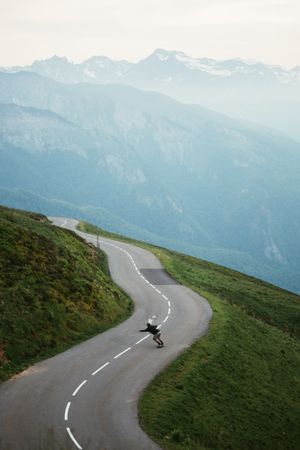 Scenic mountains view and man skateboarding on road