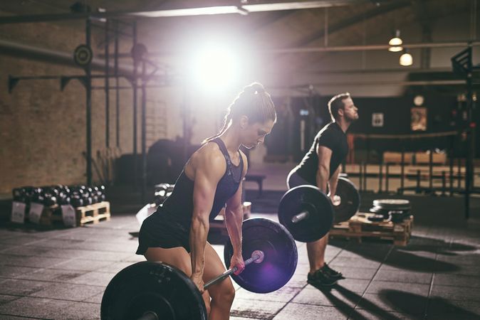 Focused athletes using correct lifting form for strength training exercise