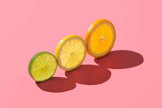 Citrus fruits variety, single slices isolated on a pink background